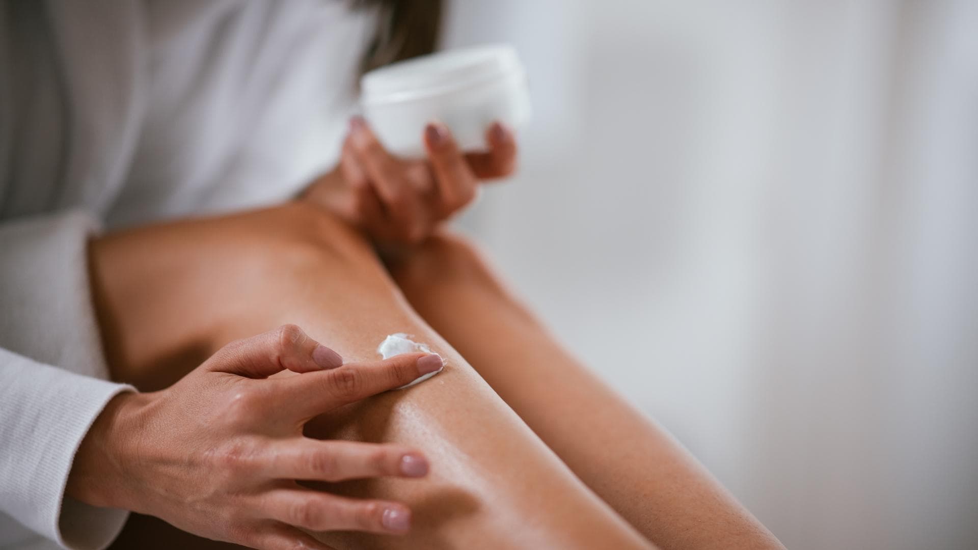 Frau cremt Beine ein