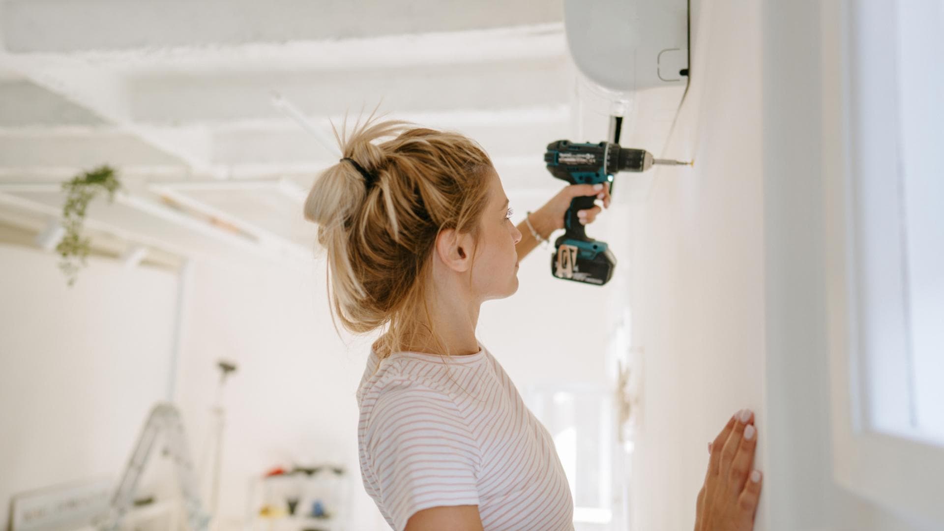 Frau bohrt Loch in Wand