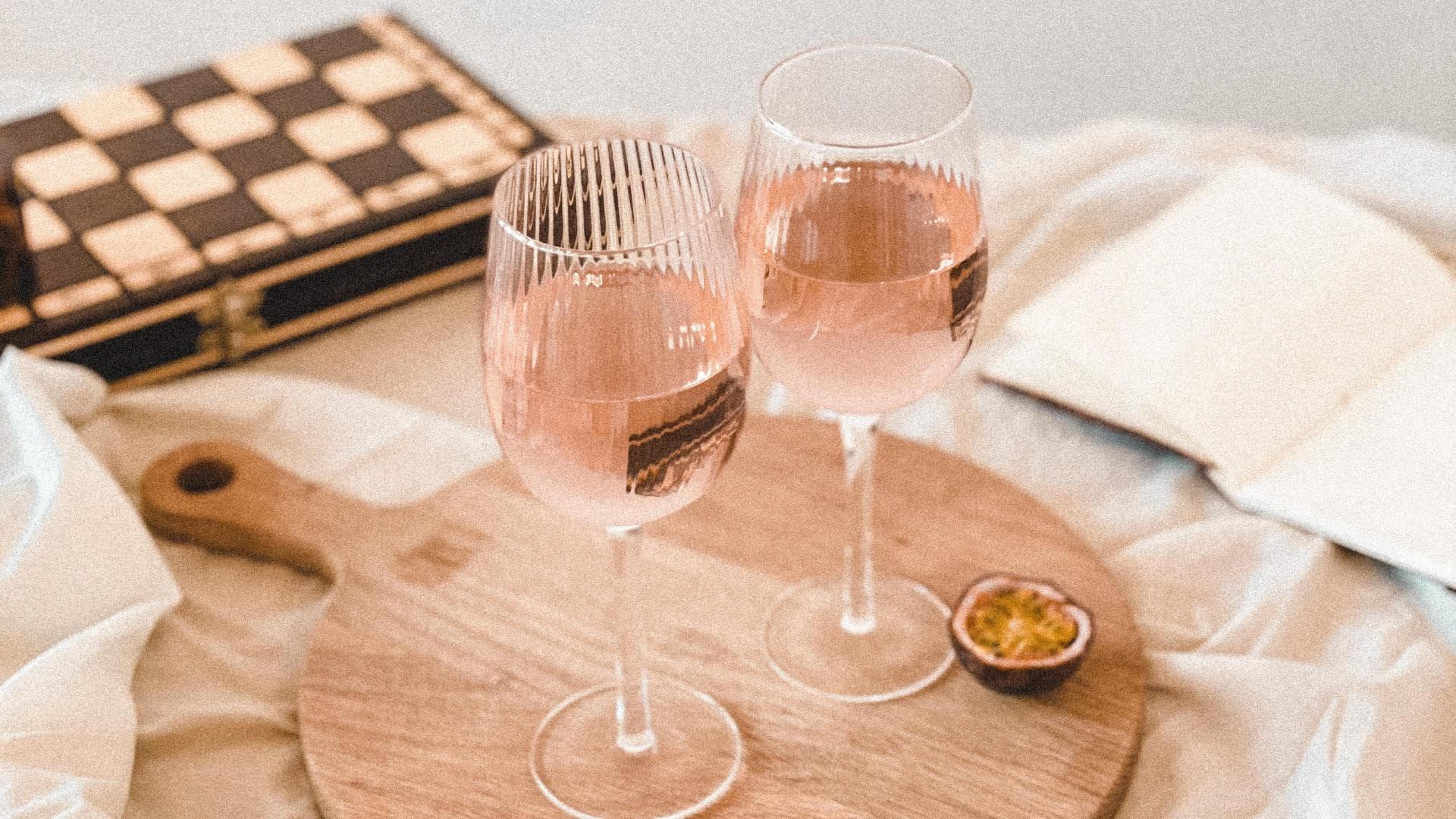 Zwei Gläser Rosé stehen auf einem Holzbrett.