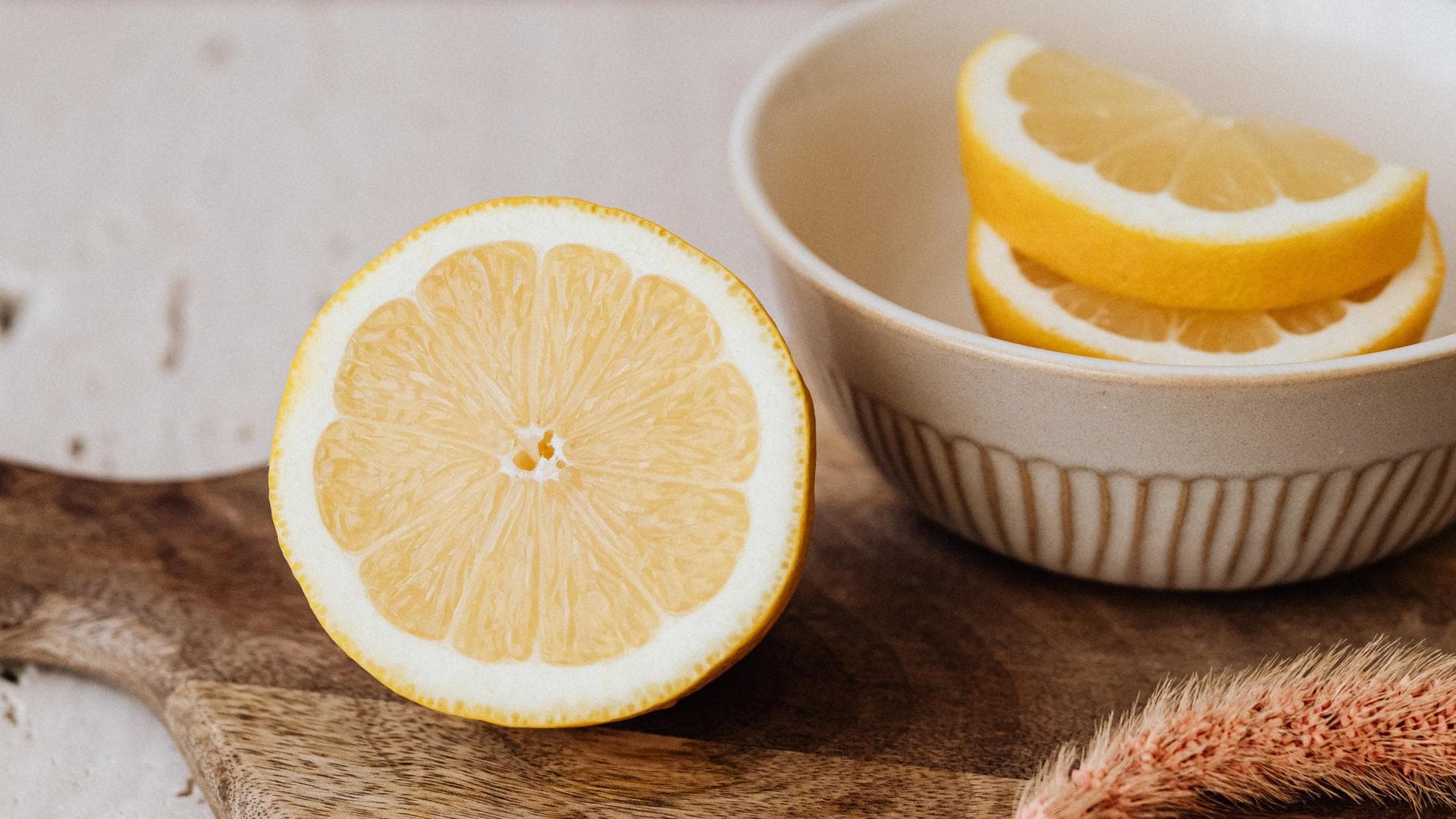 Eine angeschnittene Zitrone liegt auf einem Holzbrett.