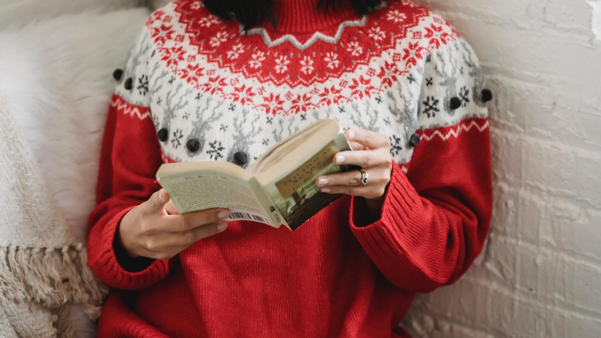 Frau mit Weihnachtsmütze liest Weihnachtsroman.