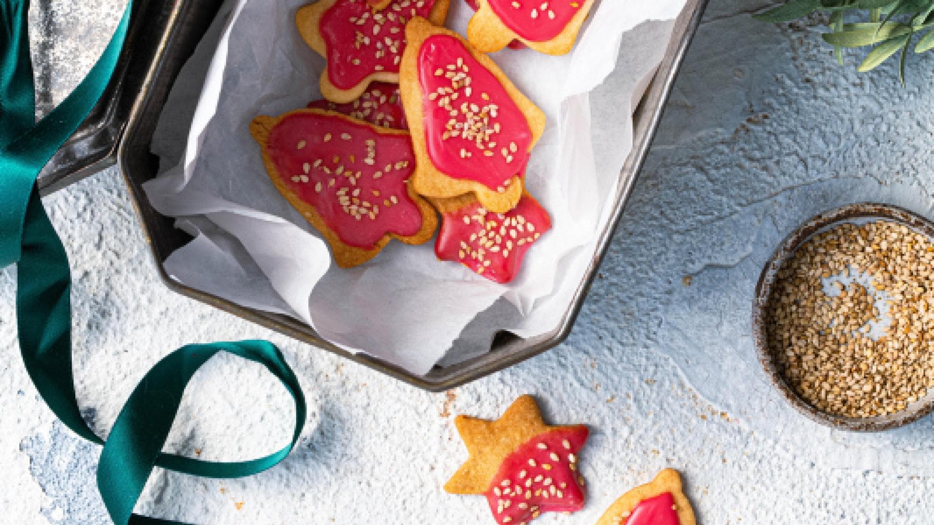 Weihnachtlich verzierte Sesamkekse in einer Blechkiste.