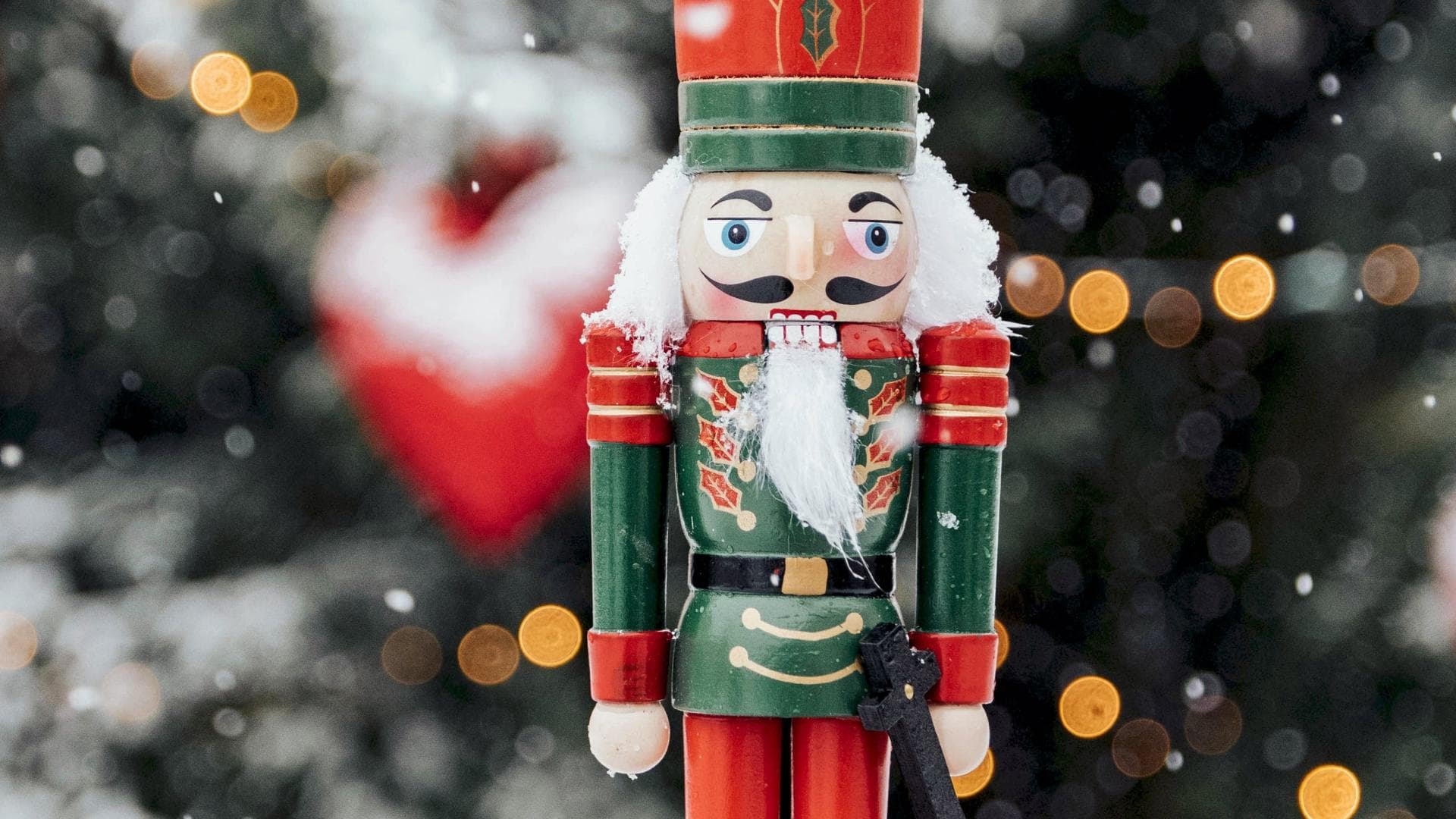 Frau hält einen Nussknacker vor winterlichen Hintergrund.