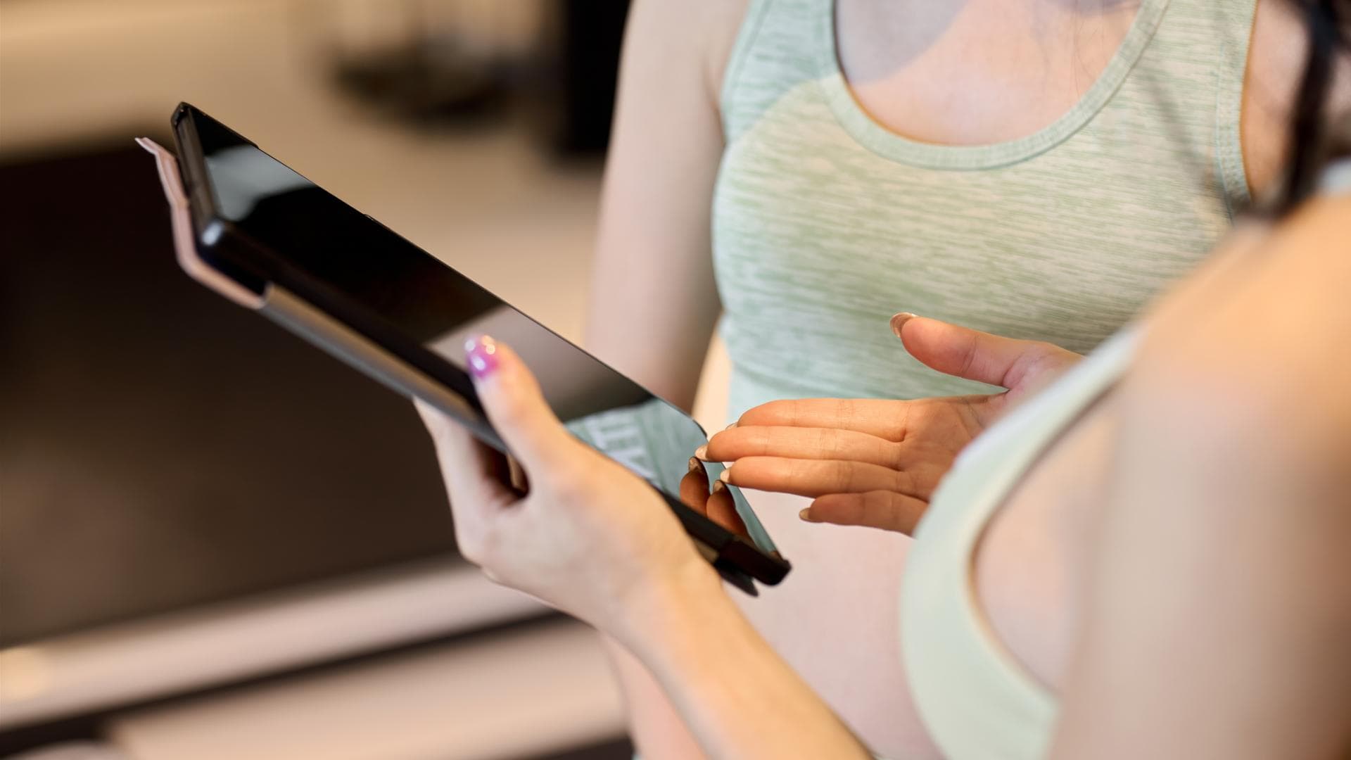 Frau zeigt kostenlose Trainingspläne auf dem Tablet