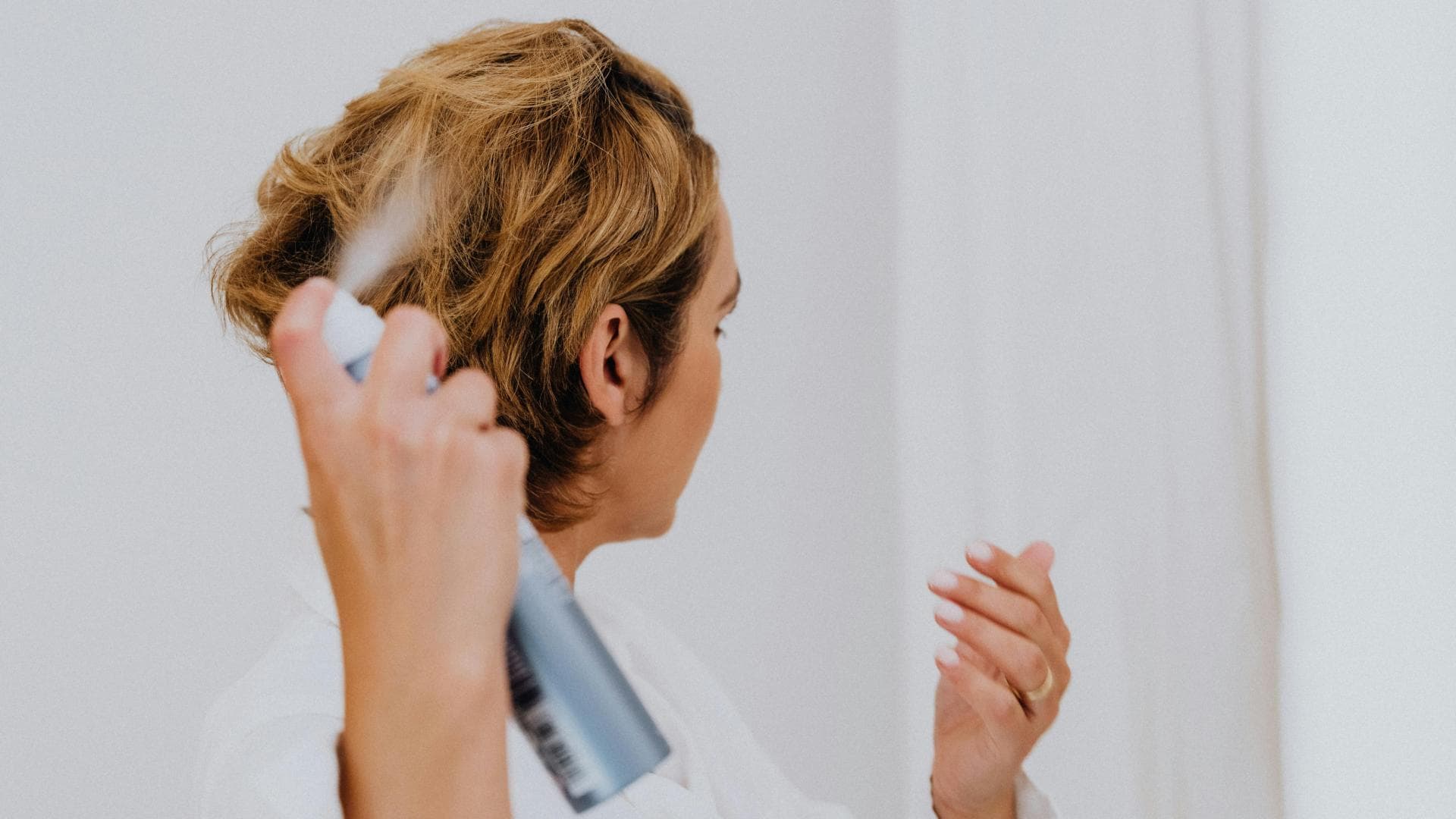 Frau sprüht Haarspray