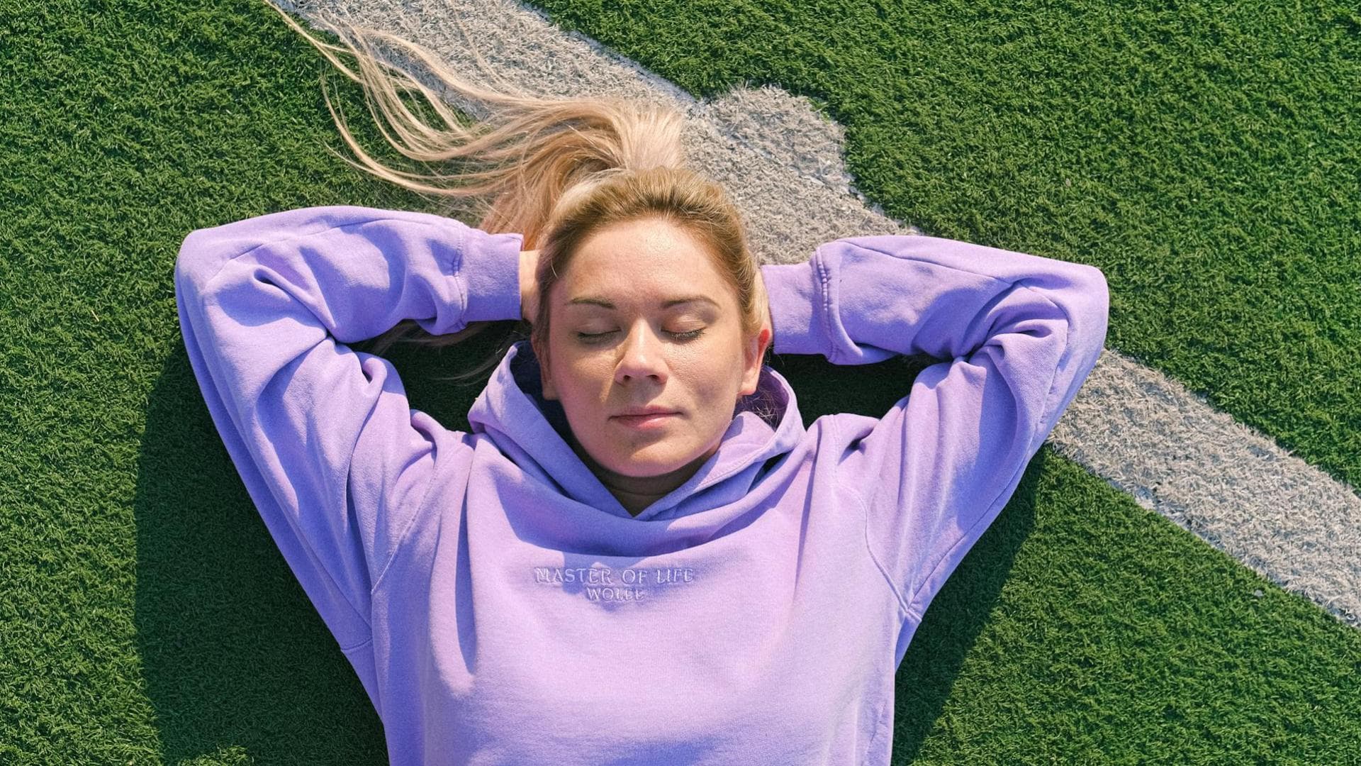 Frau liegt auf dem Rücken mit verschränkten Armen hinter dem Kopf