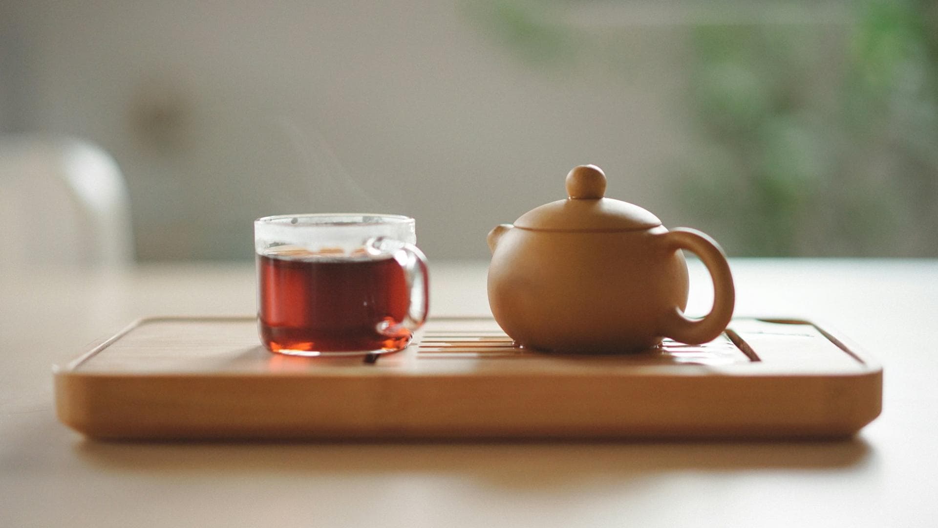Yogi Tee in einem Glas mit Teekanne daneben