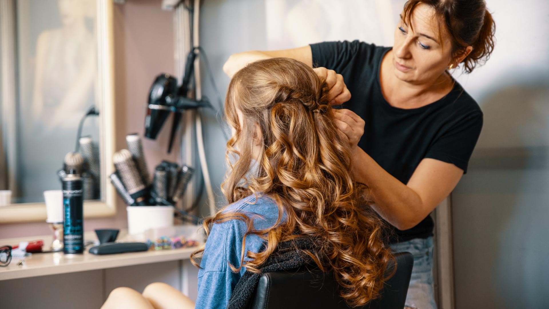 Frau macht einer anderen Frau eine festliche Frisur mit Locken