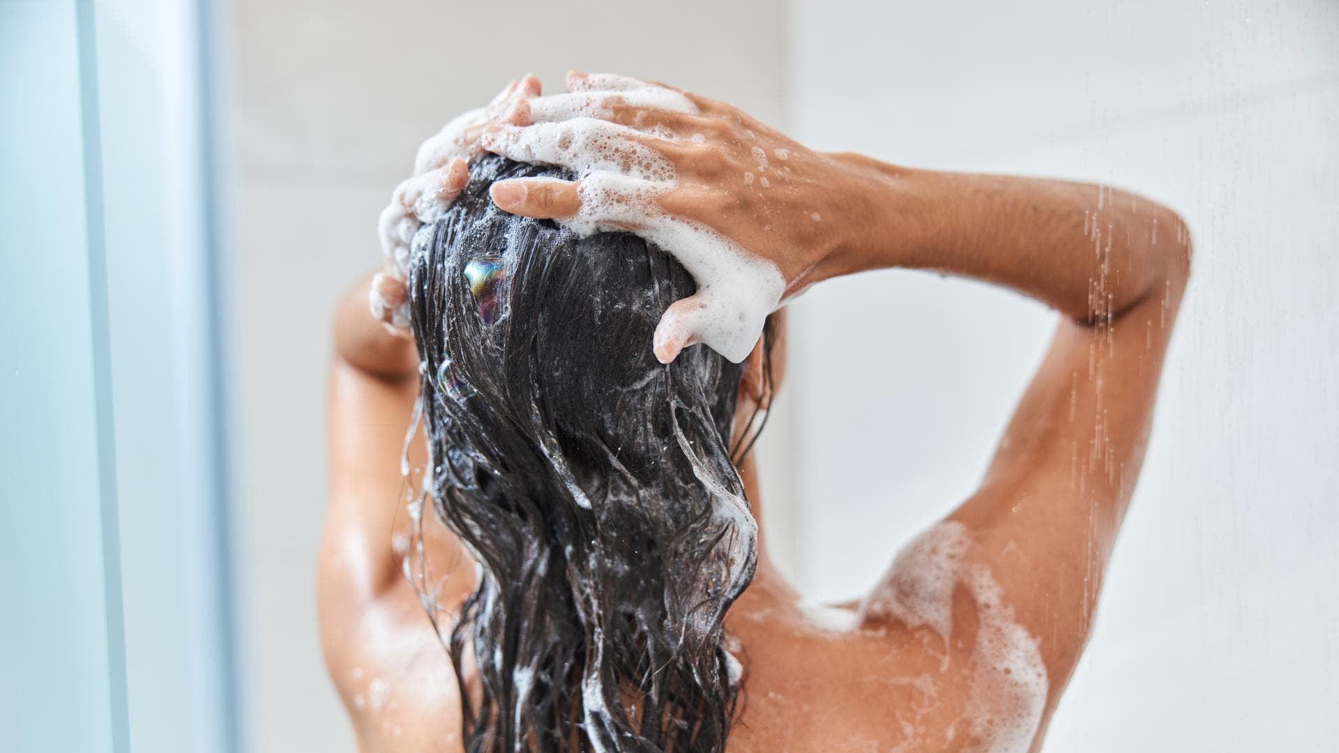 Frau shampooniert Haare ein