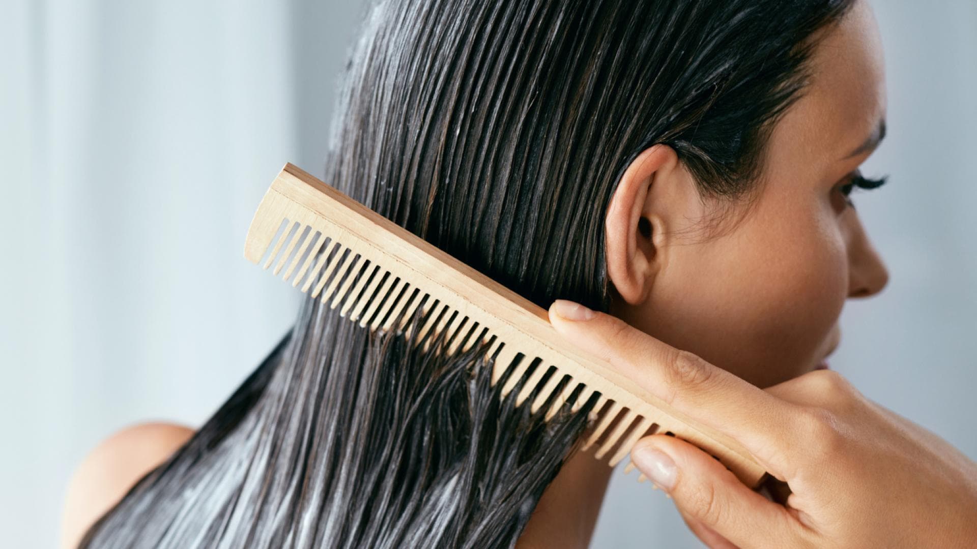 Frau kämmt Haarpflegeprodukt ein