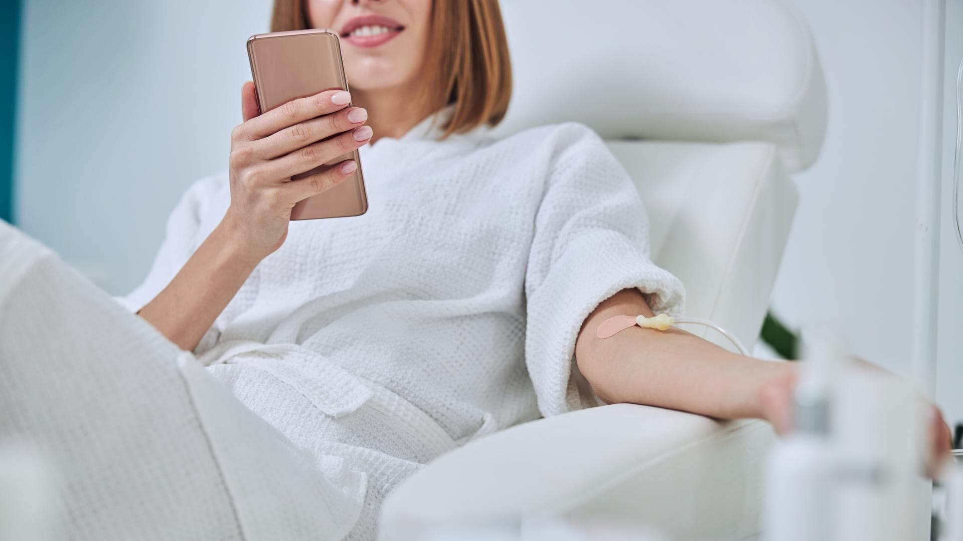 Frau am Handy bekommt eine Infusion