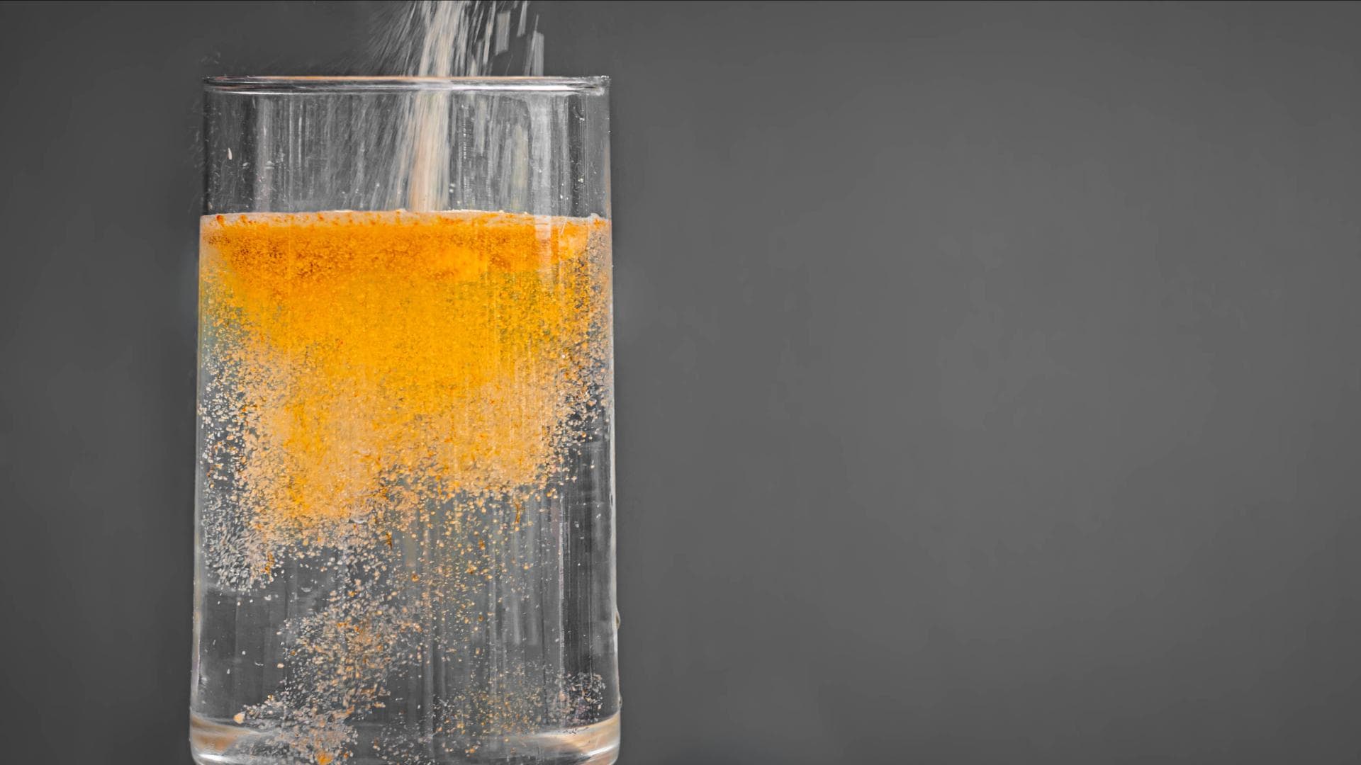 Glas Wasser mit orangefarbener Brause