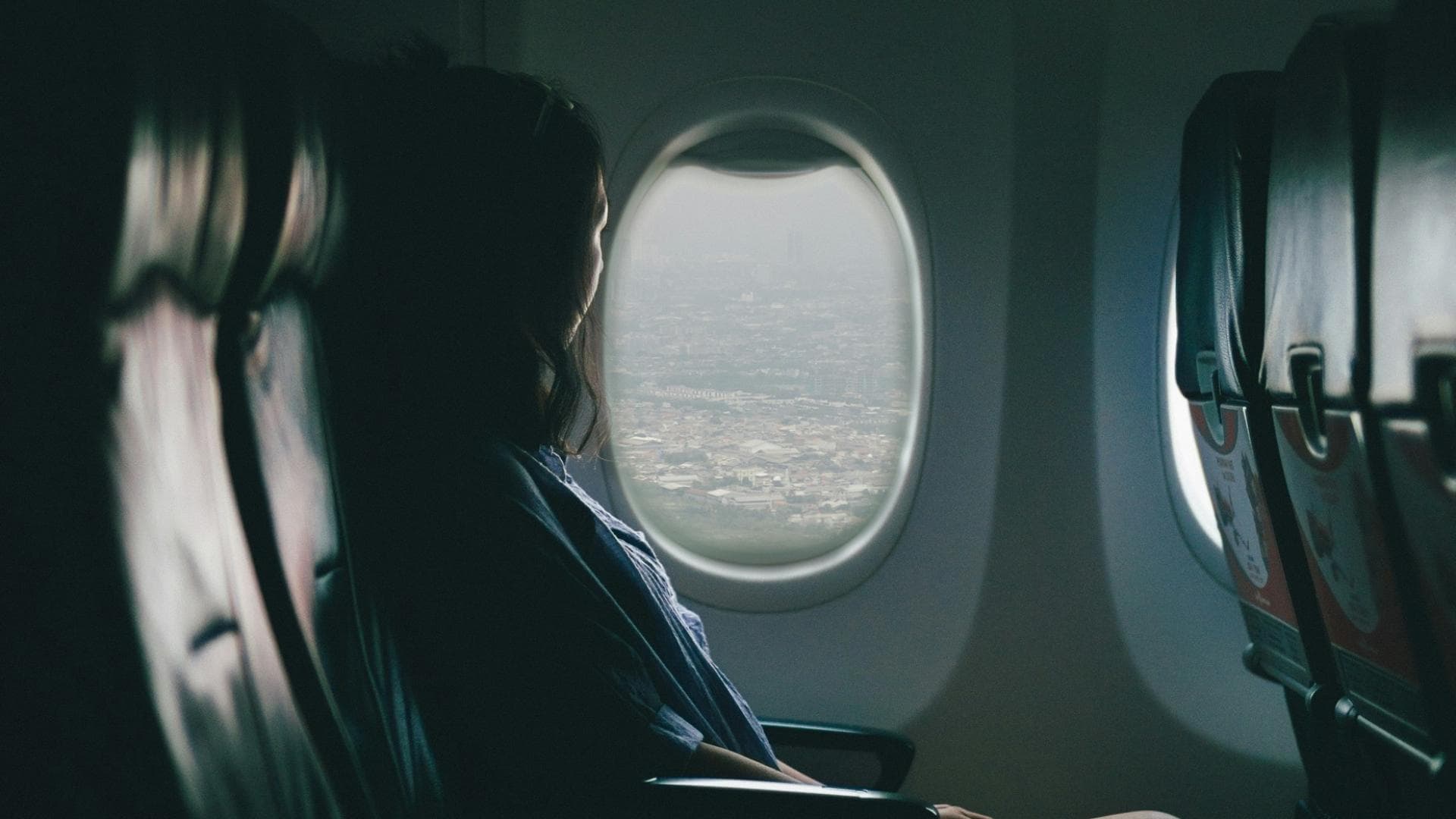 Frau sitzt im Flugzeug am Fenster.