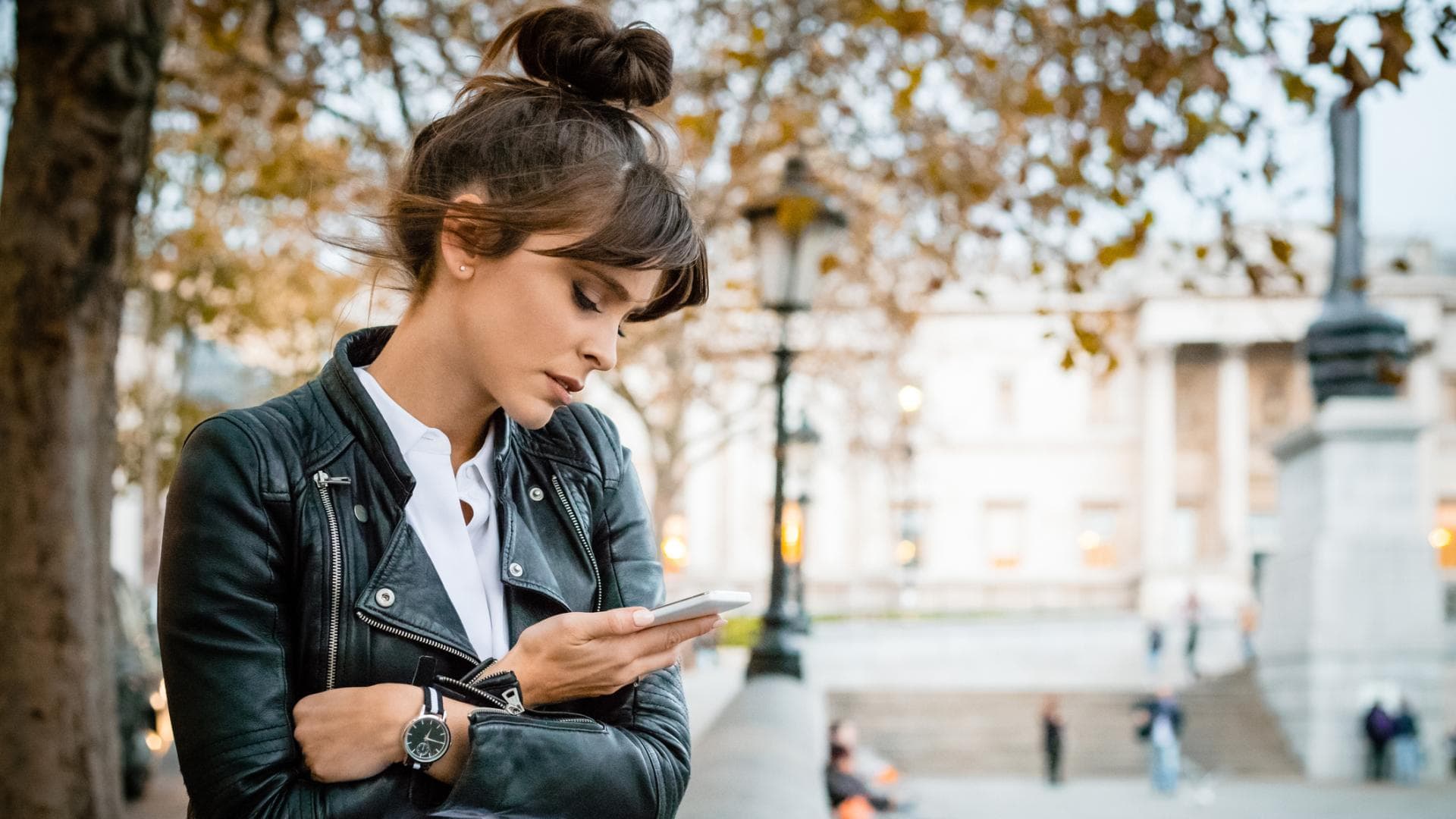 Frau schaut wartend auf ihr Handy.