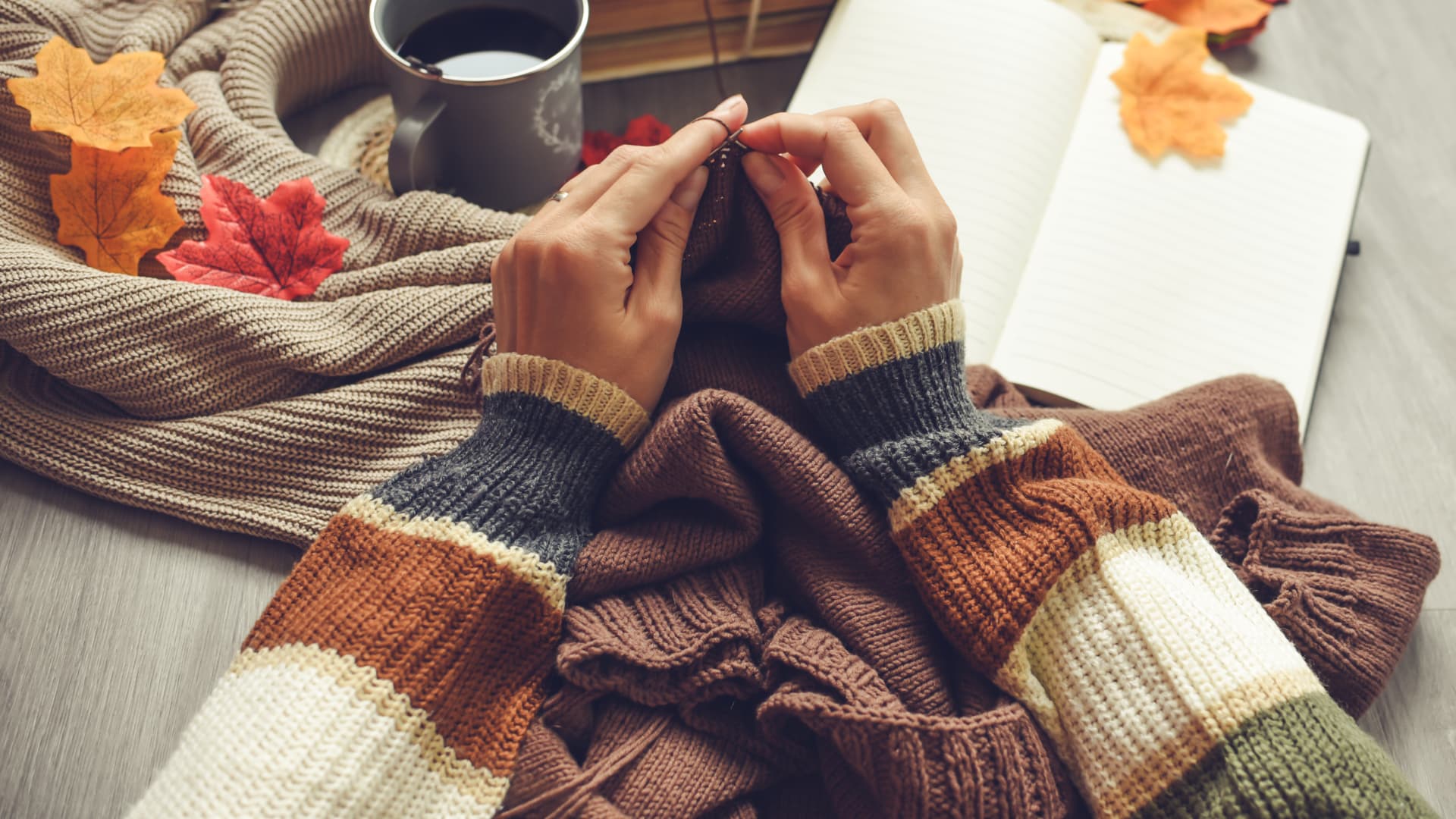 Frau strickt und hat ein Strickbuch parat