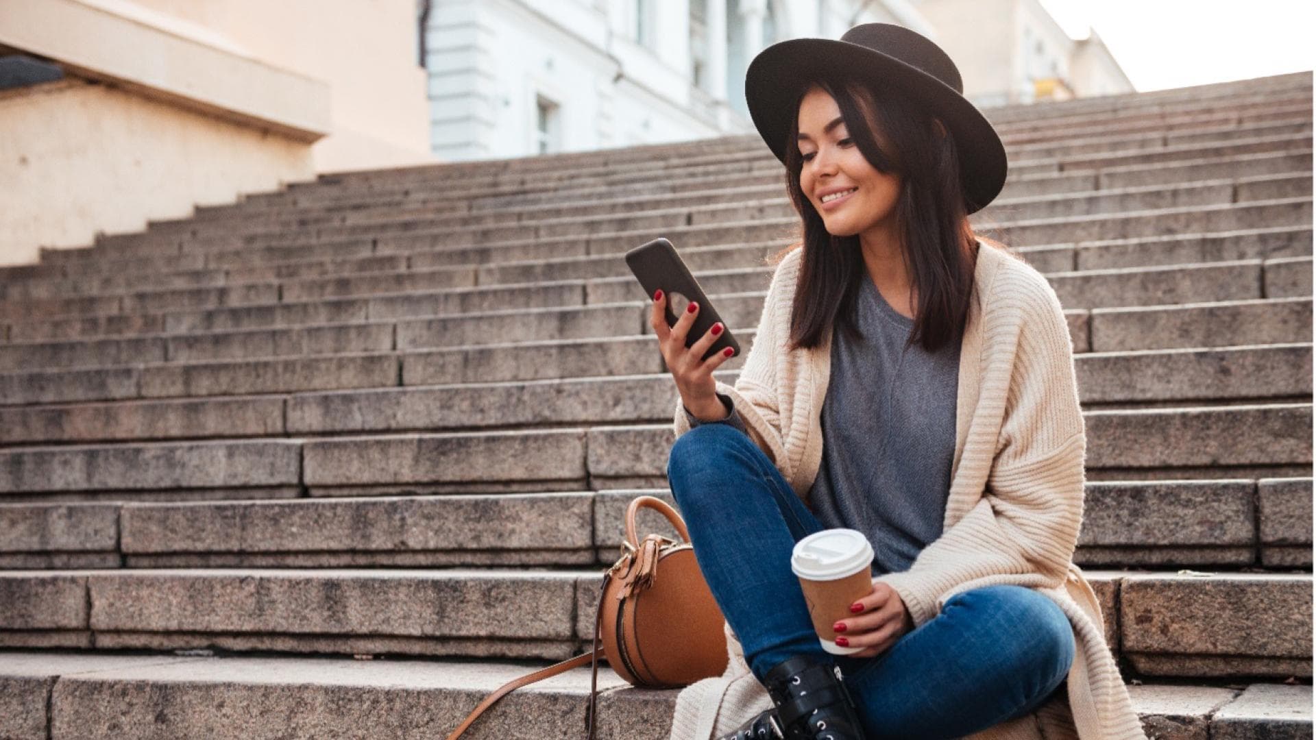 Frau sitzt auf einer Treppe und scrollt am Smartphone