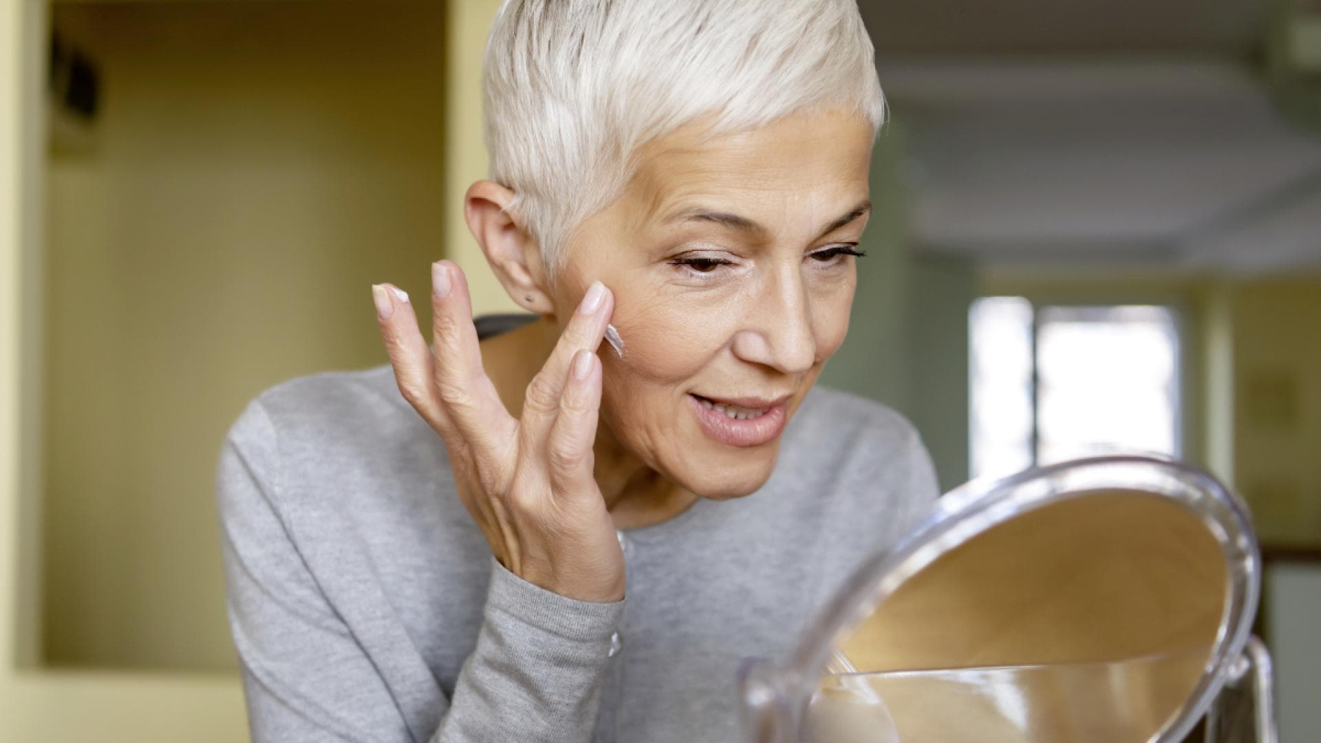 Reife Frau benutzt Anti-Aging-Produkte