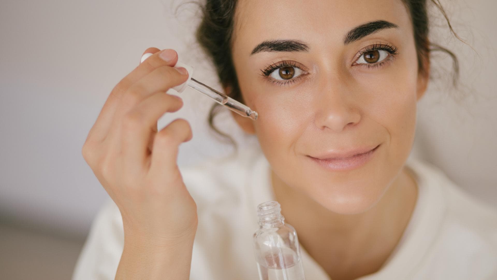 Brünette trägt Hyaluron auf die Haut auf