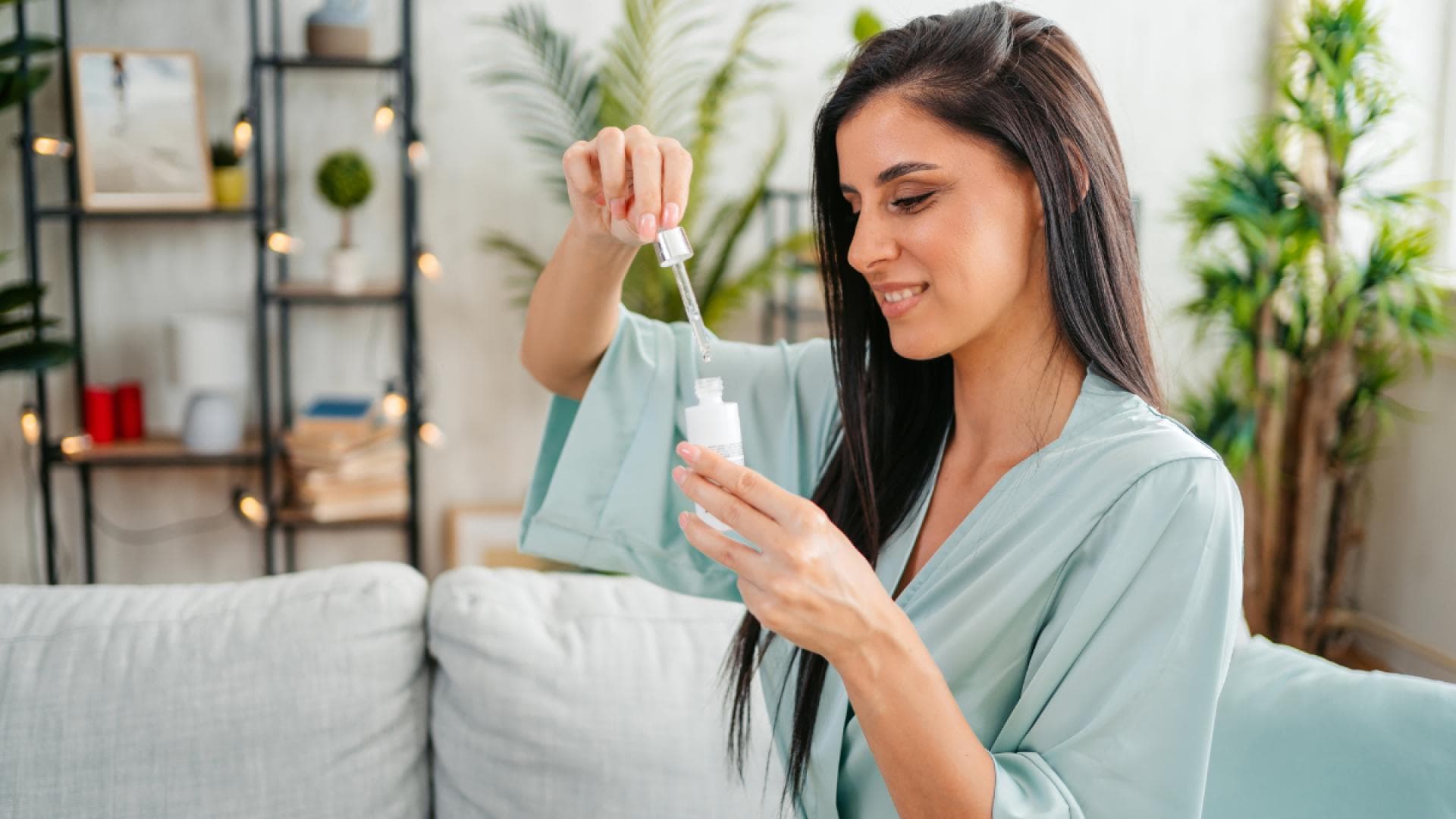 Frau im blauen Bademantel mit Serum