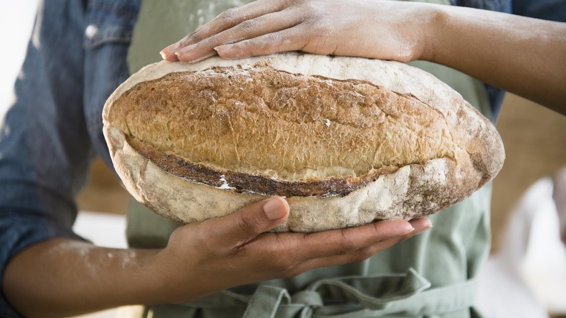 Frau hält selbstgebackenes Roggenbrot in den Händen - Das Backrezept gibt es hier