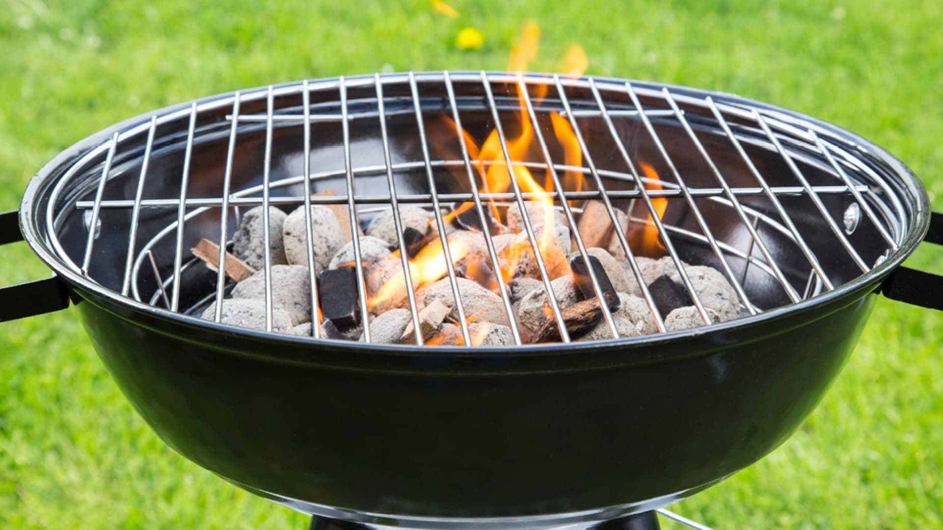 Schwarzer Holzkohlegrill mit glühenden Kohlen und Flamme