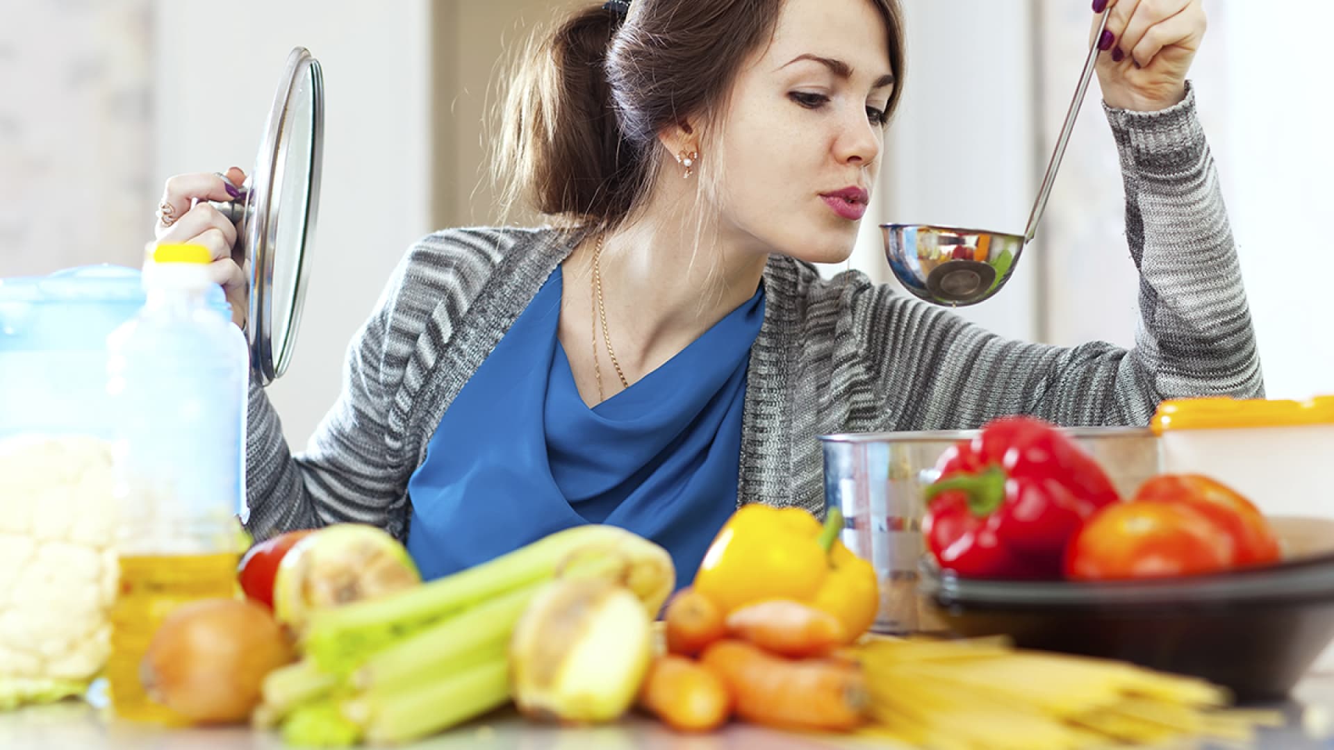 Frau kocht und probiert von einer Kelle - So kochen Sie kalorienarm und gesund