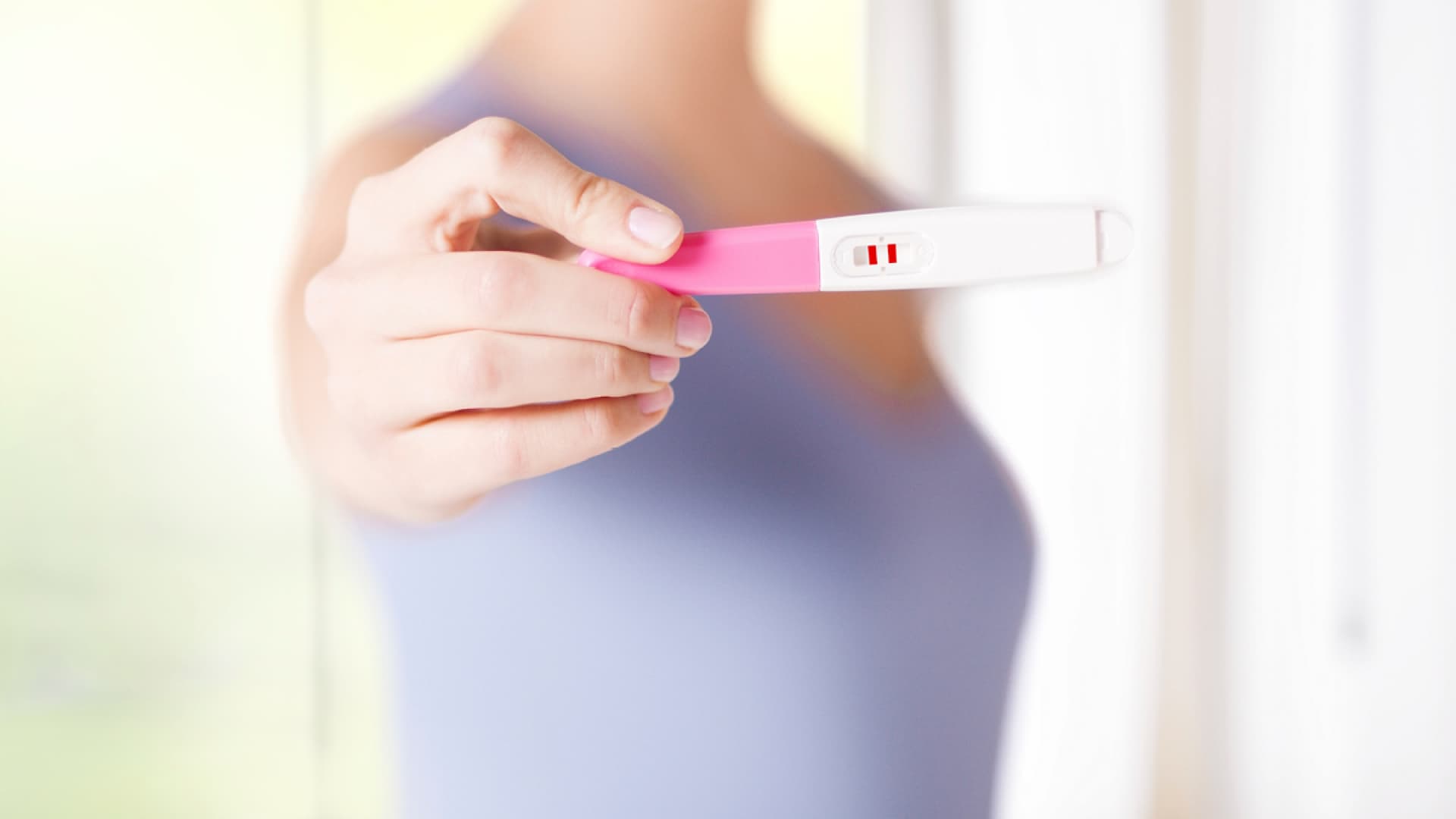 Frau zeigt ihren Schwangerschaftstest - Finden Sie hier Antworten auf 5 Fragen zur künstlichen Befruchtung 