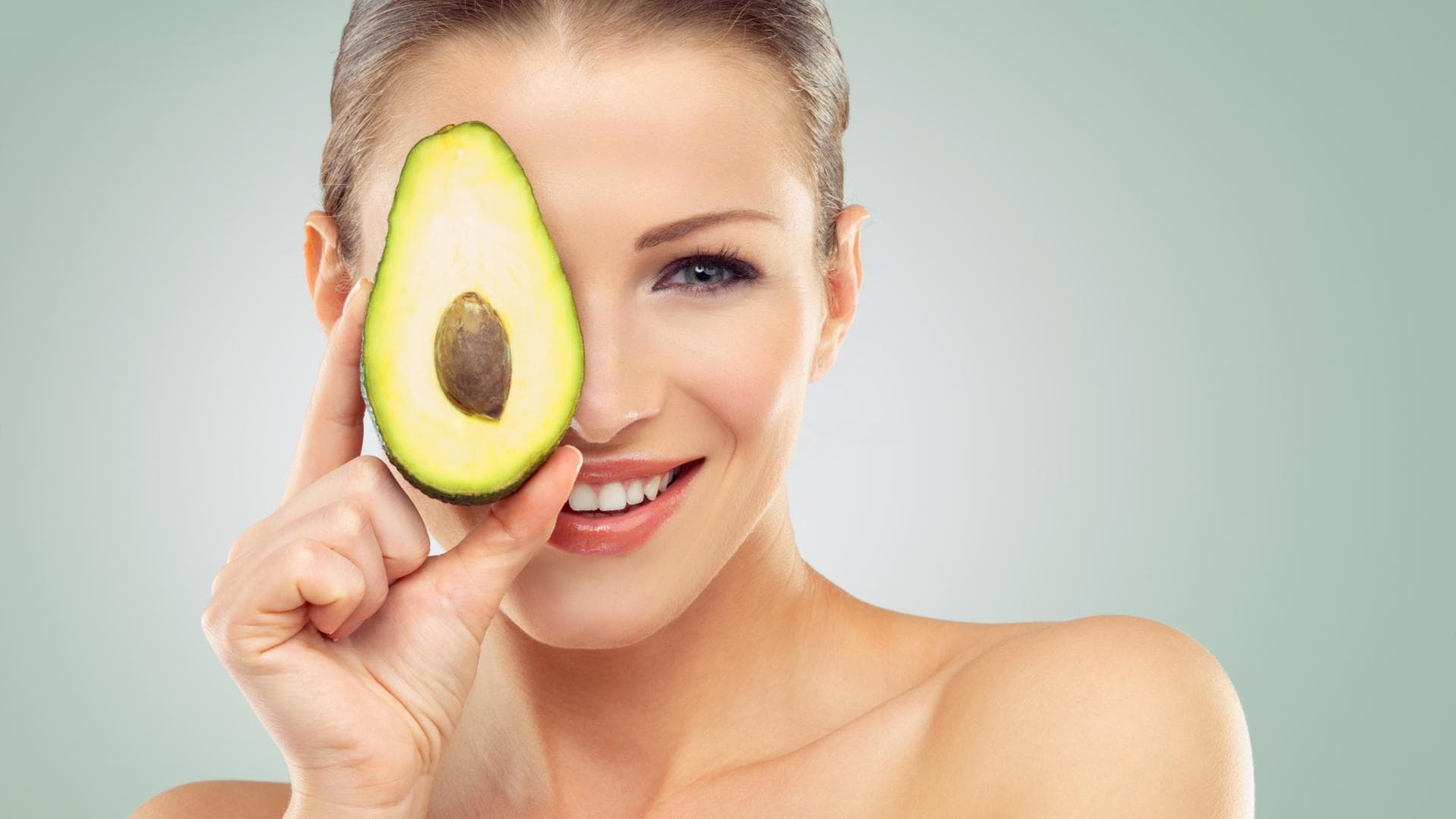 Diese Lebensmittel gelten als Fatburner: Frau hält Avocadohälfte