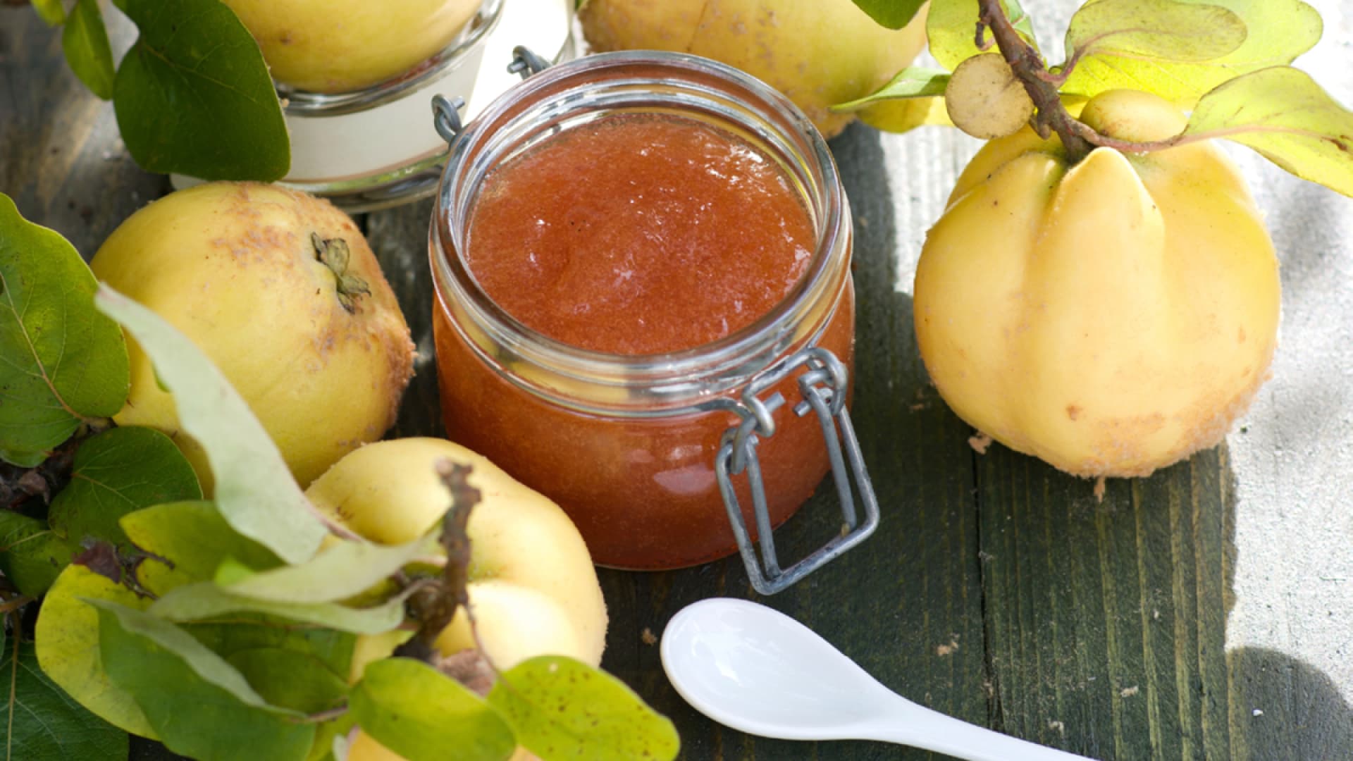 Quittenmus im Glas umgeben von Quitten