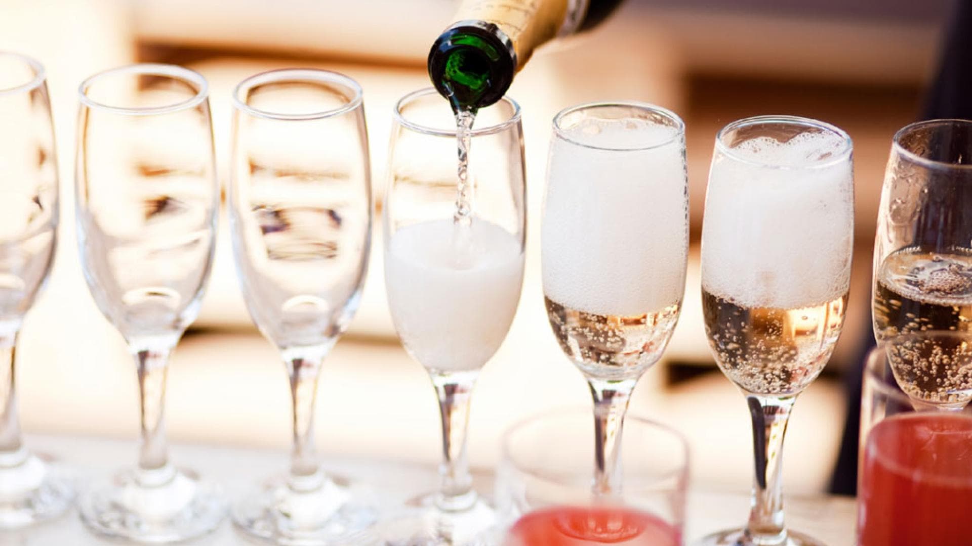 Eingießen von Sekt aus Sektflasche in mehrere Sektgläser