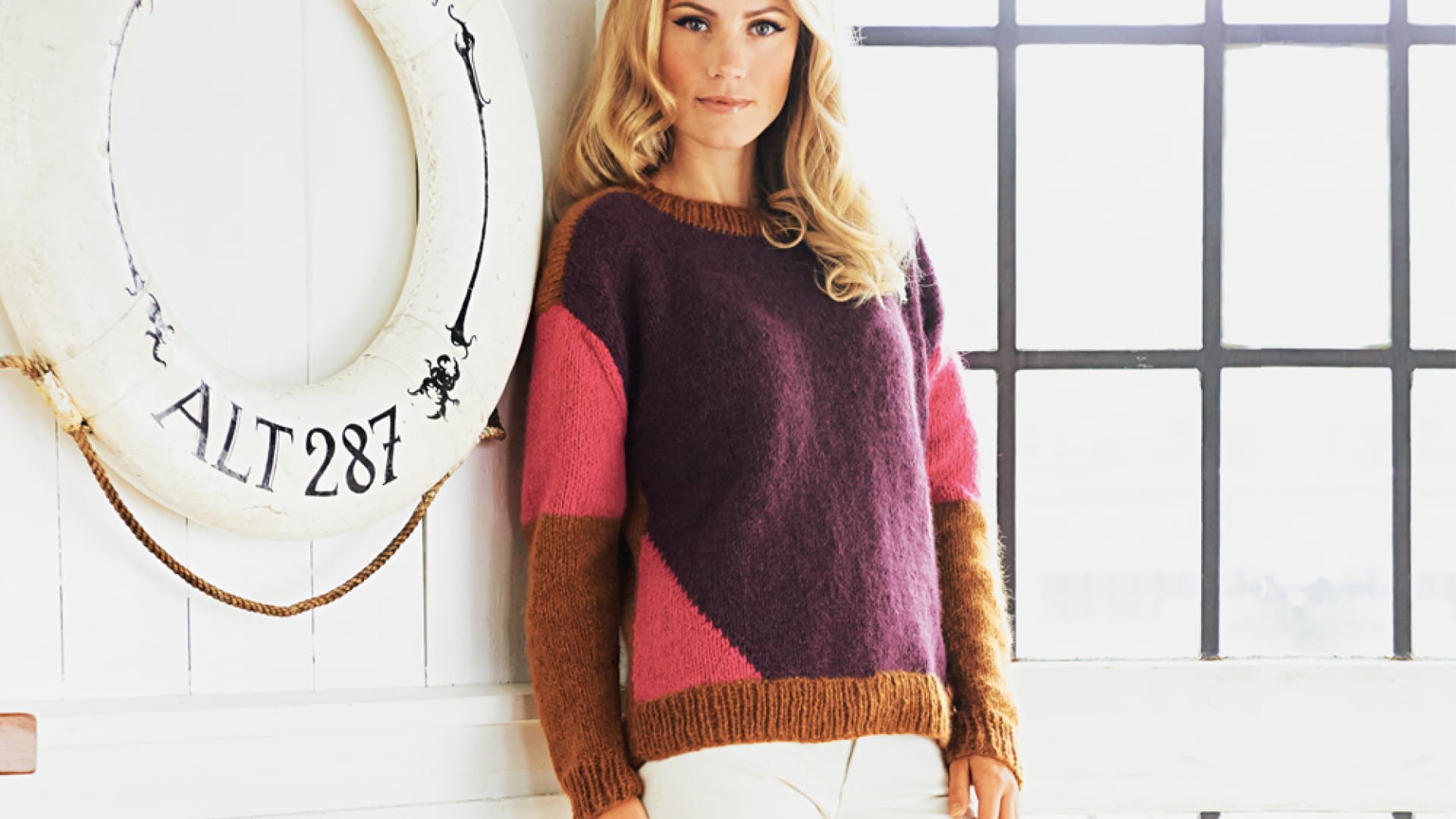 Blonde Frau in Strickpullover mit Farbflächen und vorverlegten Schultern