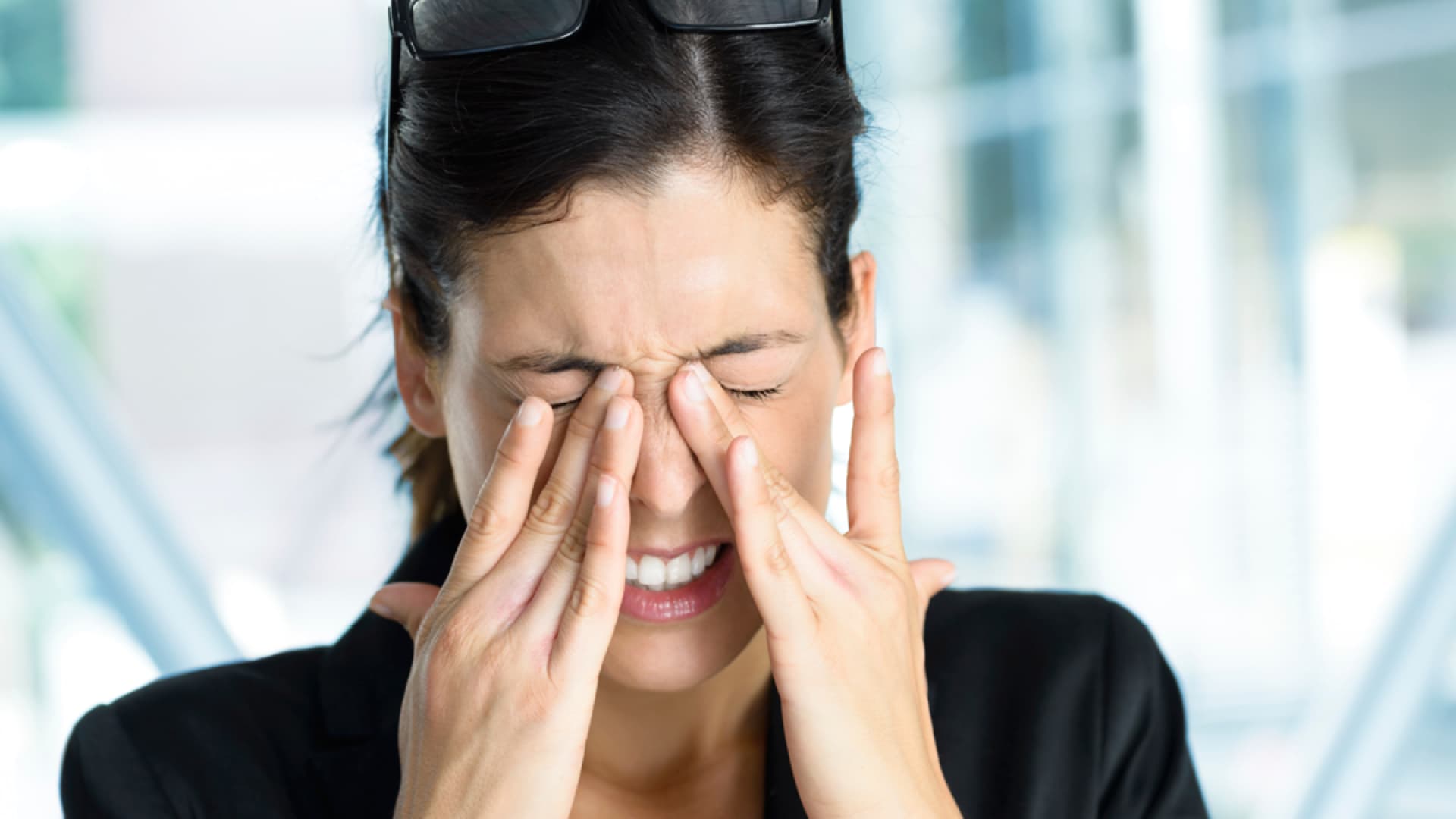 Eine Frau reibt sich ihre brennenden Augen - Hier finden Sie Ursachen für brennende Augen und wertvolle Tipps