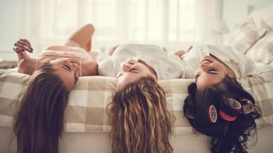 Freundinnen liegen auf dem Bett und reden