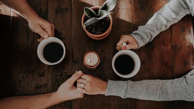 Paar hält Händchen beim Kaffeetrinken