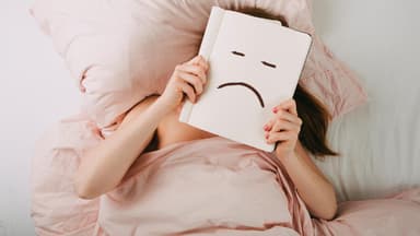 Frau liegt im Bett und schmollt