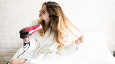Frau föhnt sich die Haare