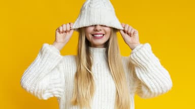 Frau mit langen Haaren zieht sich die Mütze über das Gesicht