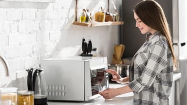 Junge Frau an der Mikrowelle 