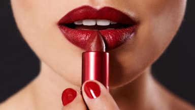Junge Frau trägt roten Lippenstift auf