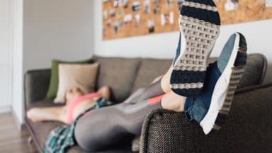 Frau in Sportkleidung auf der Couch 