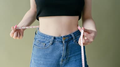 schlanke Frau misst Bauch mit Maßband