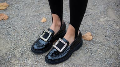 Frau trägt schwarze Loafer mit großer Schnalle.
