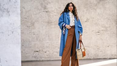 Frau in weiter Hose und blauem Mantel