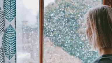 Frau steht am Fenster 