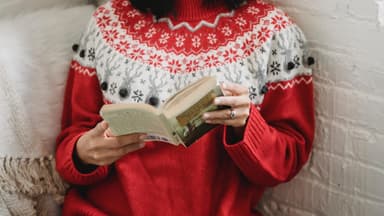 Frau mit Weihnachtsmütze liest Weihnachtsroman.