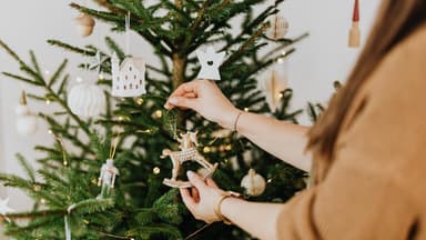 Frau schmückt Weihnachtsbaum mit Christbaumschmuck 