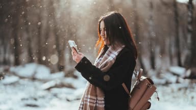Frau hält Smartphone im Winter
