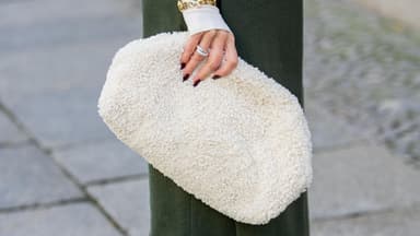 Frau hält eine weiße Teddytasche im eleganten Streetstyle.