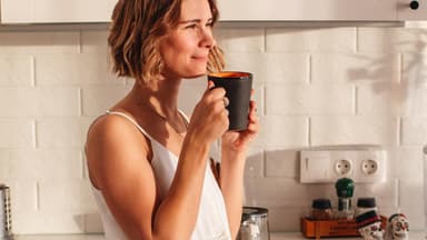 Frau trinkt Kaffee in der Küche.