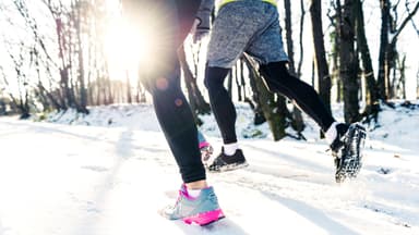 Zwei Personen joggen im Winter.